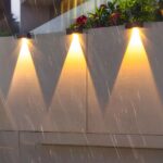 Applique LED solaire étanche et design noir Applique LED solaire étanche et design noir, au nombre de 3 avec lumière jaune sur un mur.