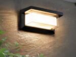 Applique murale exterieur LED à détecteur de mouvements installée sur un mur avec une plante verte devant