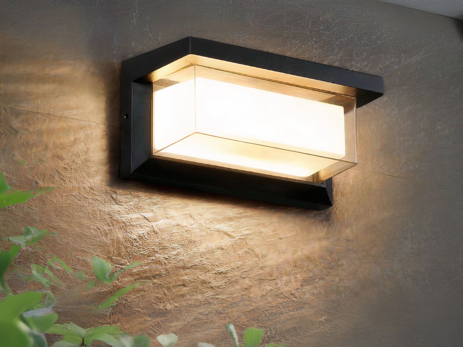 Applique murale exterieur LED à détecteur de mouvements installée sur un mur avec une plante verte devant