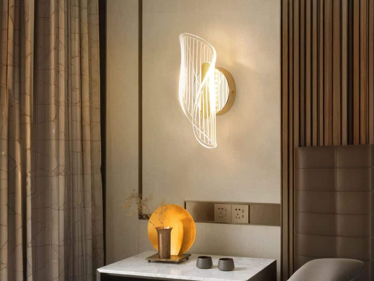 Applique murale LED moderne et luxueuse Applique murale LED luxueuse, allumée et installée sur un mur à côté d'un lit, en guise de lampe de chevet, au-dessus d'une table de nuit.