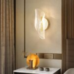 Applique murale LED moderne et luxueuse Applique murale LED luxueuse, allumée et installée sur un mur à côté d'un lit, en guise de lampe de chevet, au-dessus d'une table de nuit.