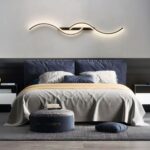 Applique murale LED noire moderne au design double S Chambre avec grand lit, une belle tête de lit bleu foncé en velours. Au-dessus, une applique murale LED noire moderne double S à l'horizontale.