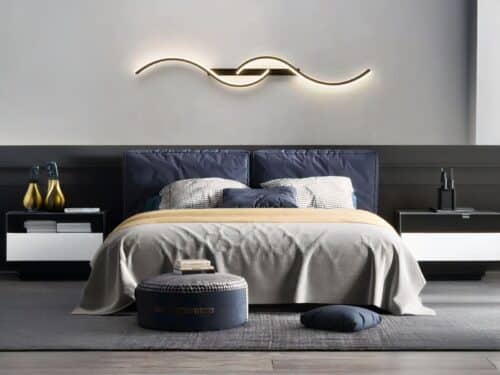 Chambre avec grand lit, une belle tête de lit bleu foncé en velours. Au-dessus, une applique murale LED noire moderne double S à l'horizontale.