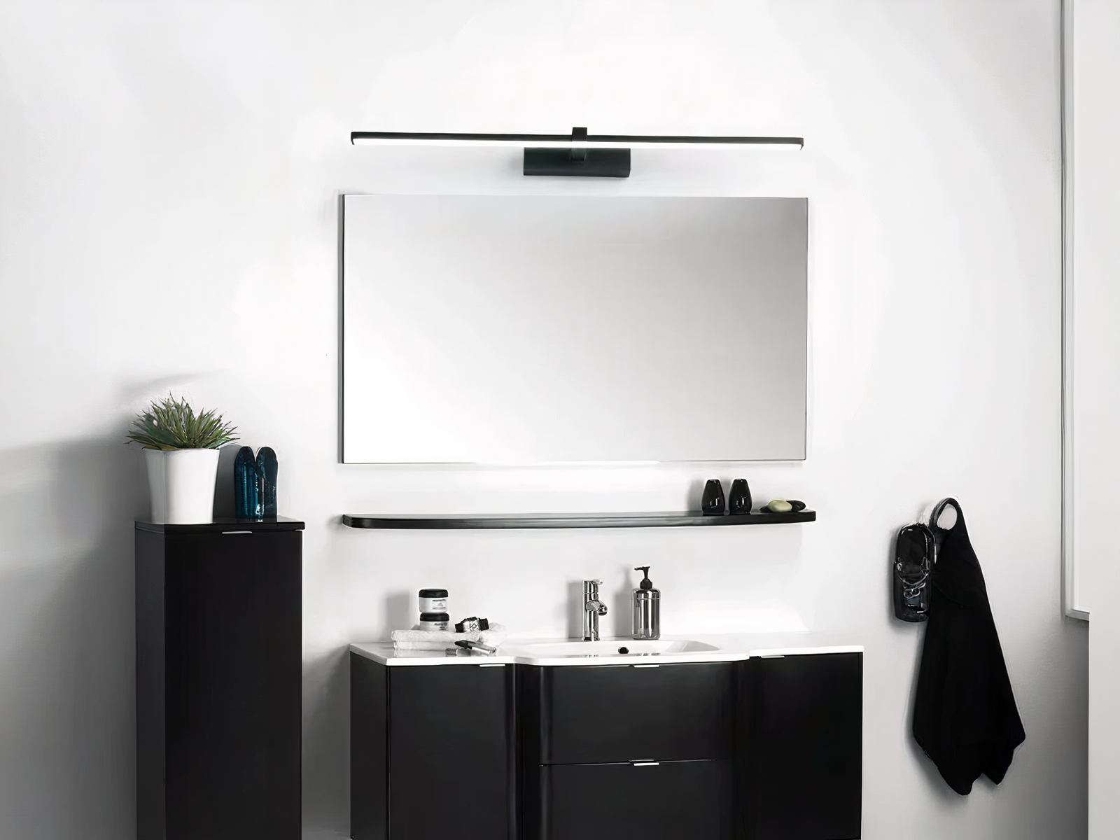 Salle de bain moderne noire et blanche, avec une meuble et lavabo au-dessus duquel est installé un miroir et une applique murale LED noire.
