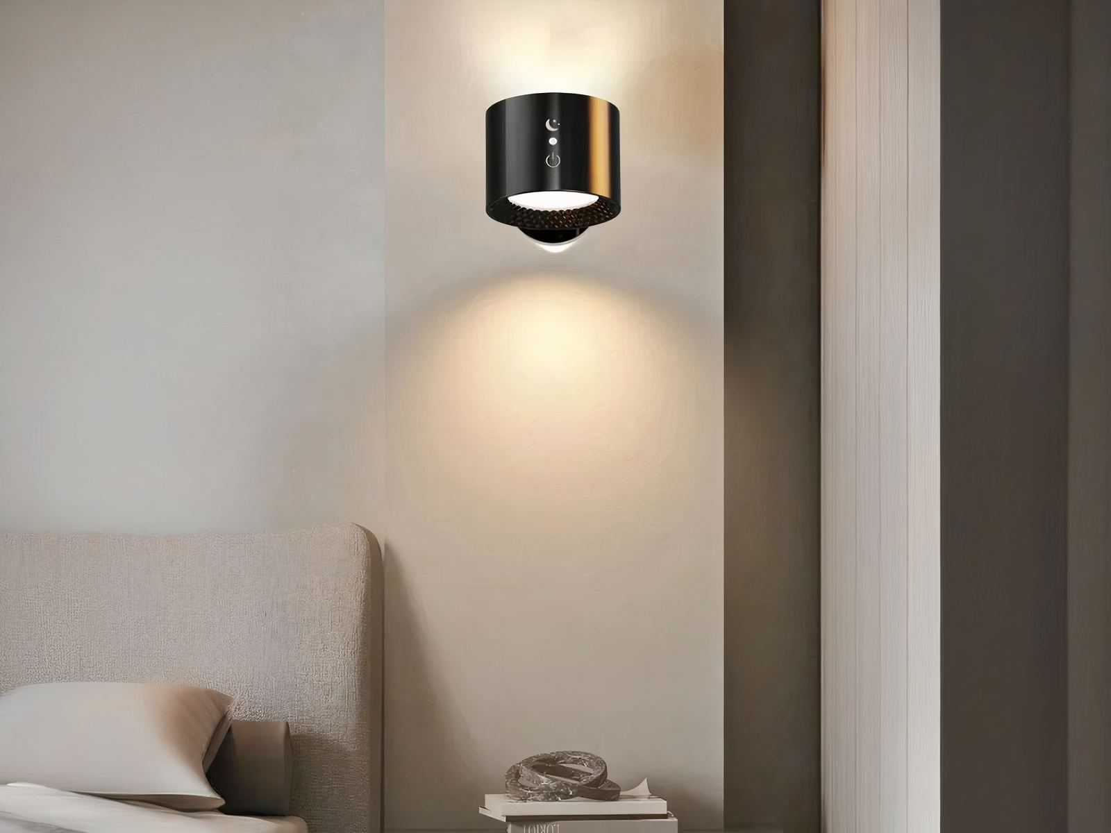 Applique murale LED sans fil rotative Applique murale LED noire, fixé au mur à côté d'un lit, en guise de lampe de chevet. La lumière est projetée par en haut et an bas.