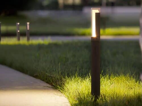 Borne extérieure LED design et étanche en aluminium, de couleur noire, dans un jardin.
