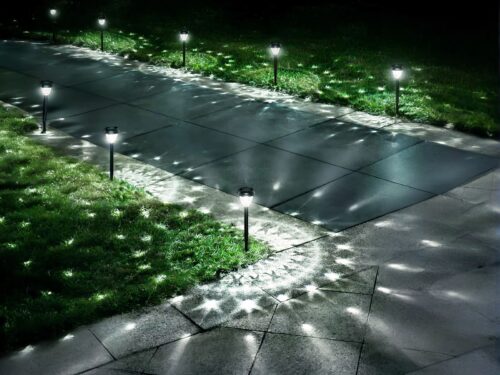 Borne extérieure LED solaire et étanche, de couleur noire, dans un jardin.