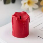 Bougie LED rouge à piles Petite bougie LED rouge effet fondu posée sur un magazine.