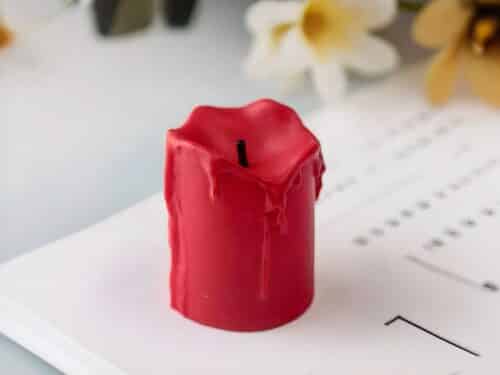 Petite bougie LED rouge effet fondu posée sur un magazine.