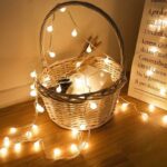 Guirlande LED à pile avec petites boules Guirlande LED à piles avec petites boules illuminées posée sur un panier en osier.