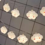 Guirlande LED à pile nuages avec sourires Guirlande LED à piles, avec des nuages qui ont un visage dessiné, installé sur un quadrillage métallique.