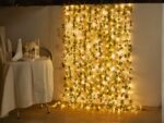 Guirlande led exterieur avec des fausses feuilles de vigne installée sur un mur avec une table à gauche