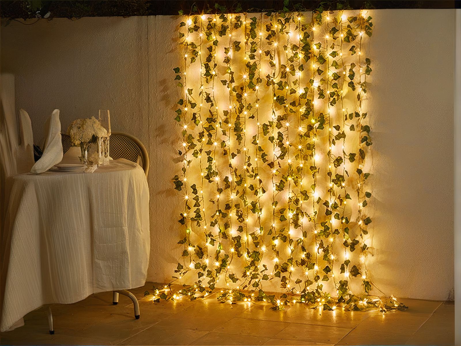 Guirlande led exterieur avec des fausses feuilles de vigne installée sur un mur avec une table à gauche