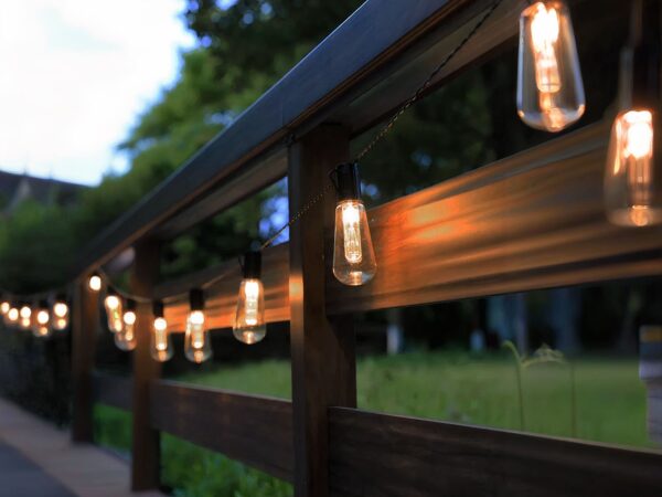 Guirlande LED solaire et étanche style vintage installée sur une barrière en bois