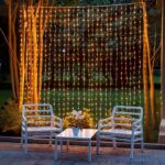 Guirlande LED solaire style rideau lumineux Guirlande LED solaire style rideau lumineux installée entre deux arbres avec une table et des chaises devant et une foret en fond