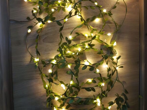 Guirlande mini LED élégante avec feuilles vertes, avec lumière jaune positionné sur le sol.