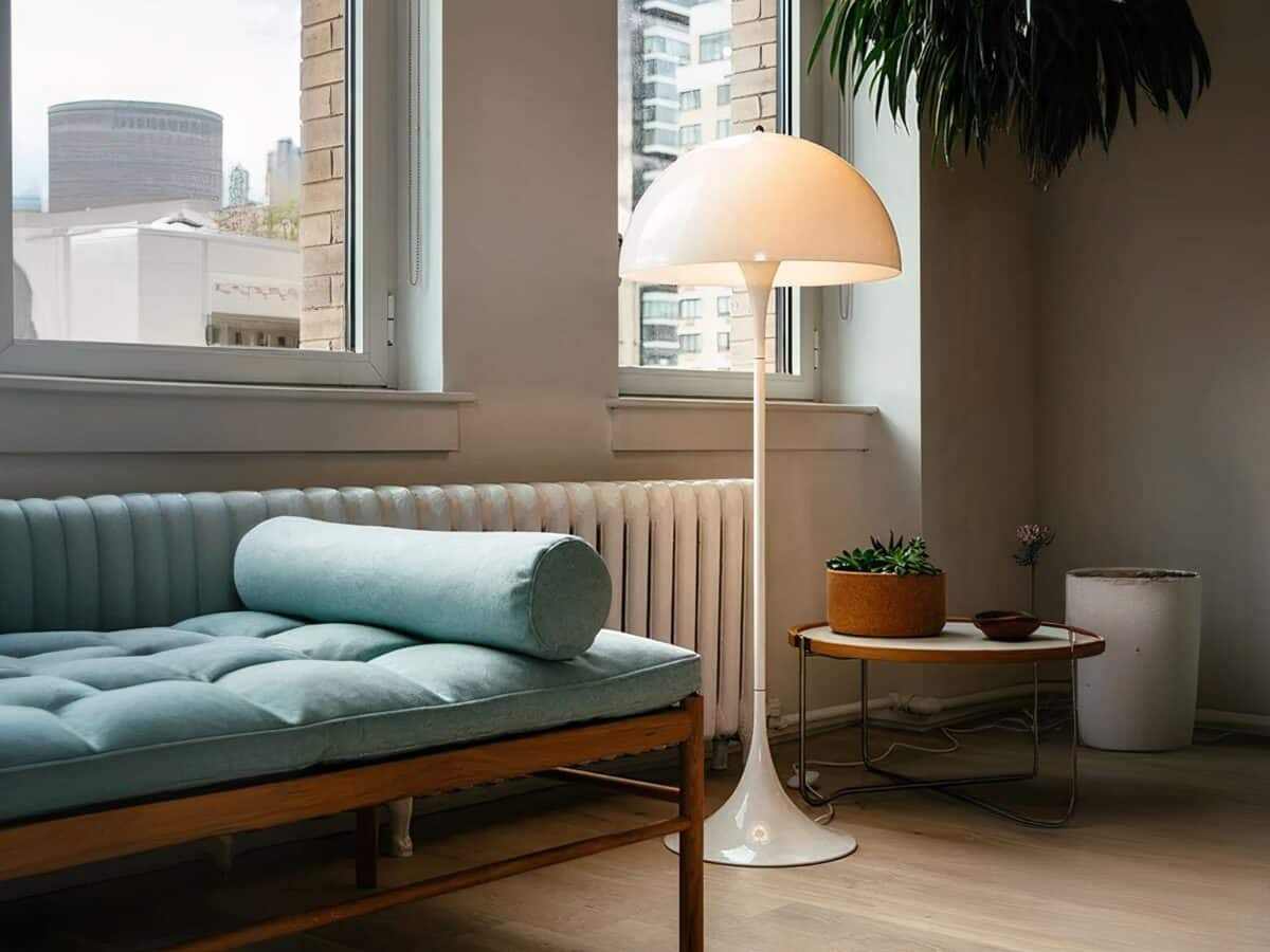 Lampadaire LED blanc moderne abat-jour champignon Lampadaire LED champignon blanc, installé dans un salon, à côté d'un chauffage et d'un sofa avec des coussins vert.