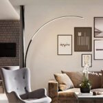 Lampadaire LED en arc-de-cercle minimaliste et moderne Lampadaire LED en arc-de-cercle noir, allumé et installé dans un salon à côté d'un canapé et d'un fauteuil.