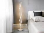 Lampadaire LED blanc, en spirale au design moderne, installé à côté d'un lit.