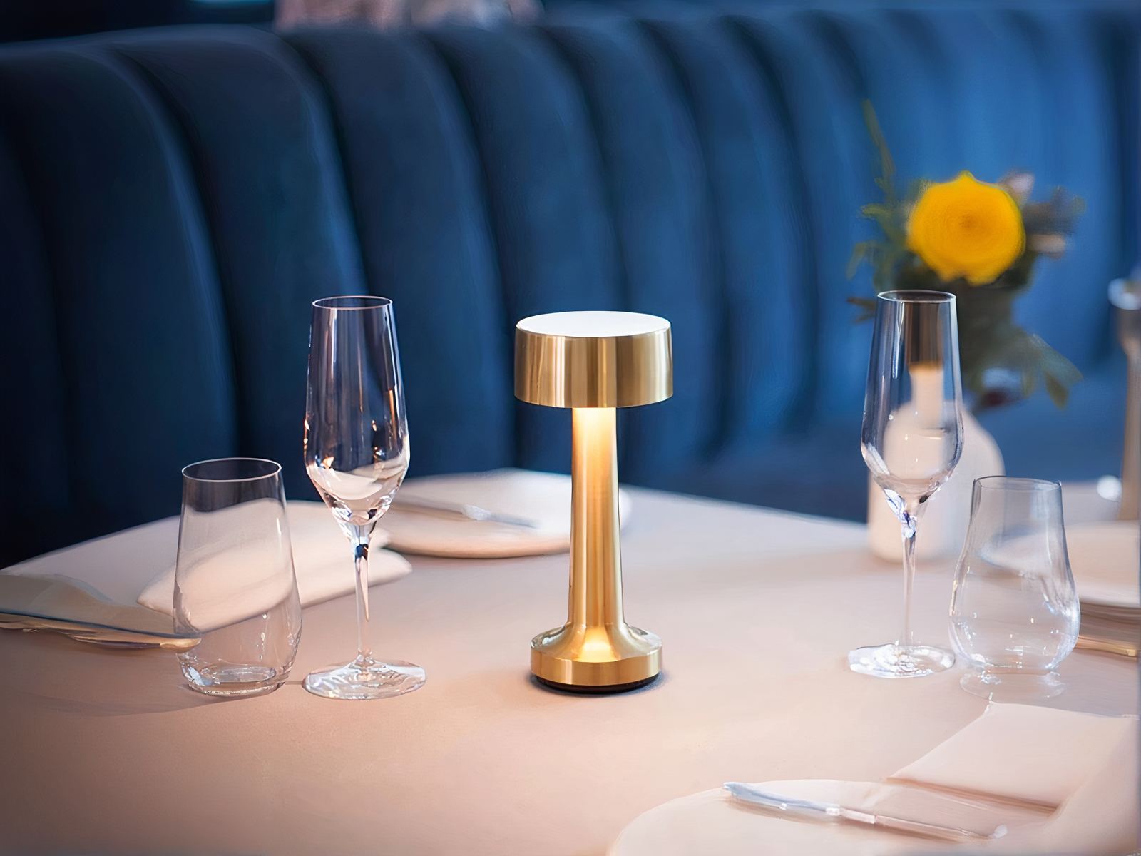 Lampe à poser LED dorée élégante et design, sur une table.