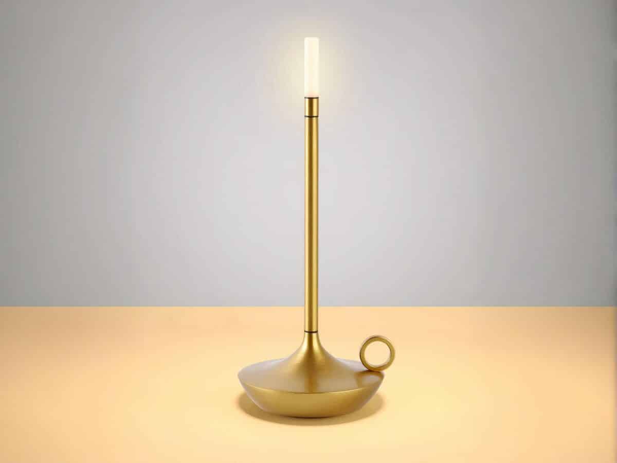 Lampe à poser LED dorée élégante et rechargeable, en forme de bougie sur une table.