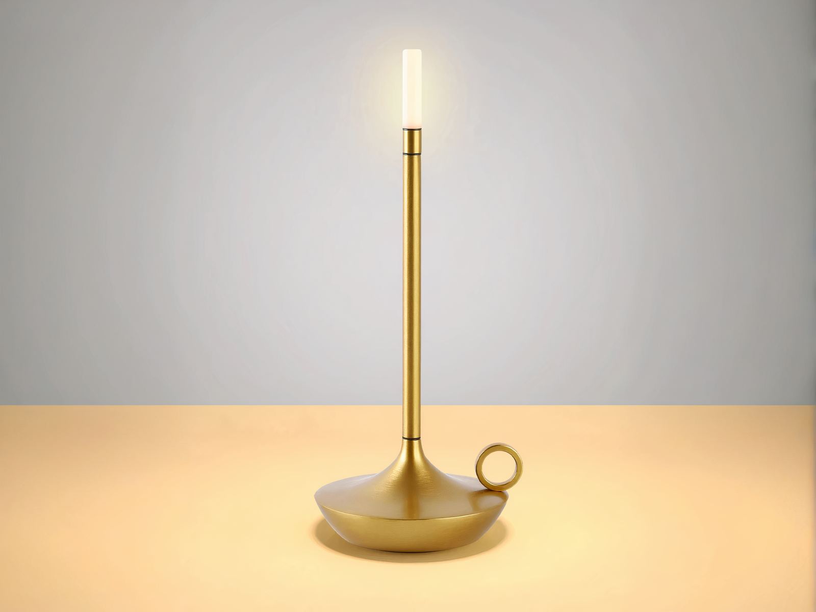 Lampe à poser LED dorée élégante et rechargeable, en forme de bougie sur une table.