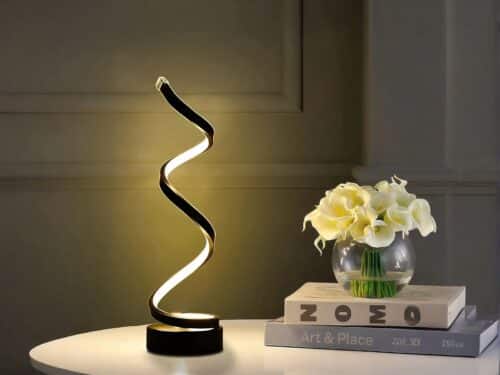 Lampe à poser LED noire à spirale, sur une table blanche.