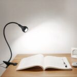 Lampe de bureau LED noire flexible et réglable Lampe de bureau LED noir flexible et réglable allumée à un bureau avec un livre posé sur le bureau