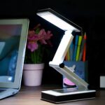 Lampe de bureau LED pliable au design futuriste Lampe de bureau LED pliable au design futuriste allumée sur un bureau dans le noir