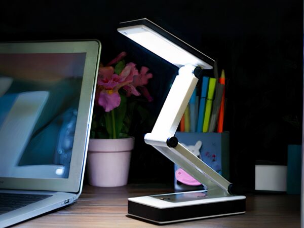 Lampe de bureau LED pliable au design futuriste allumée sur un bureau dans le noir