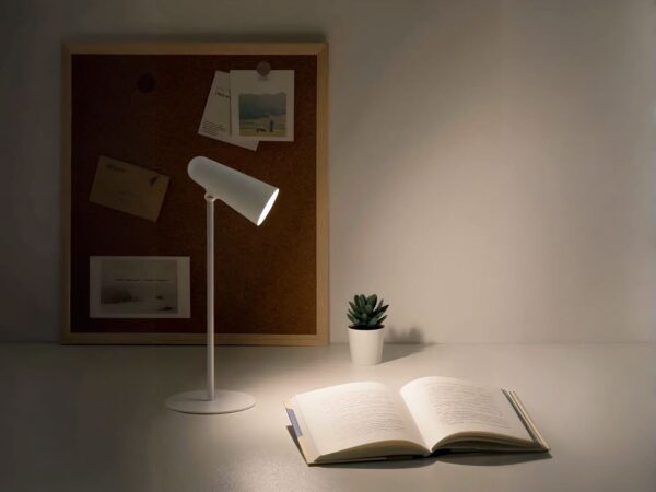 Lampe de bureau LED portative et polyvalente qui éclaire un livre sur un bureau