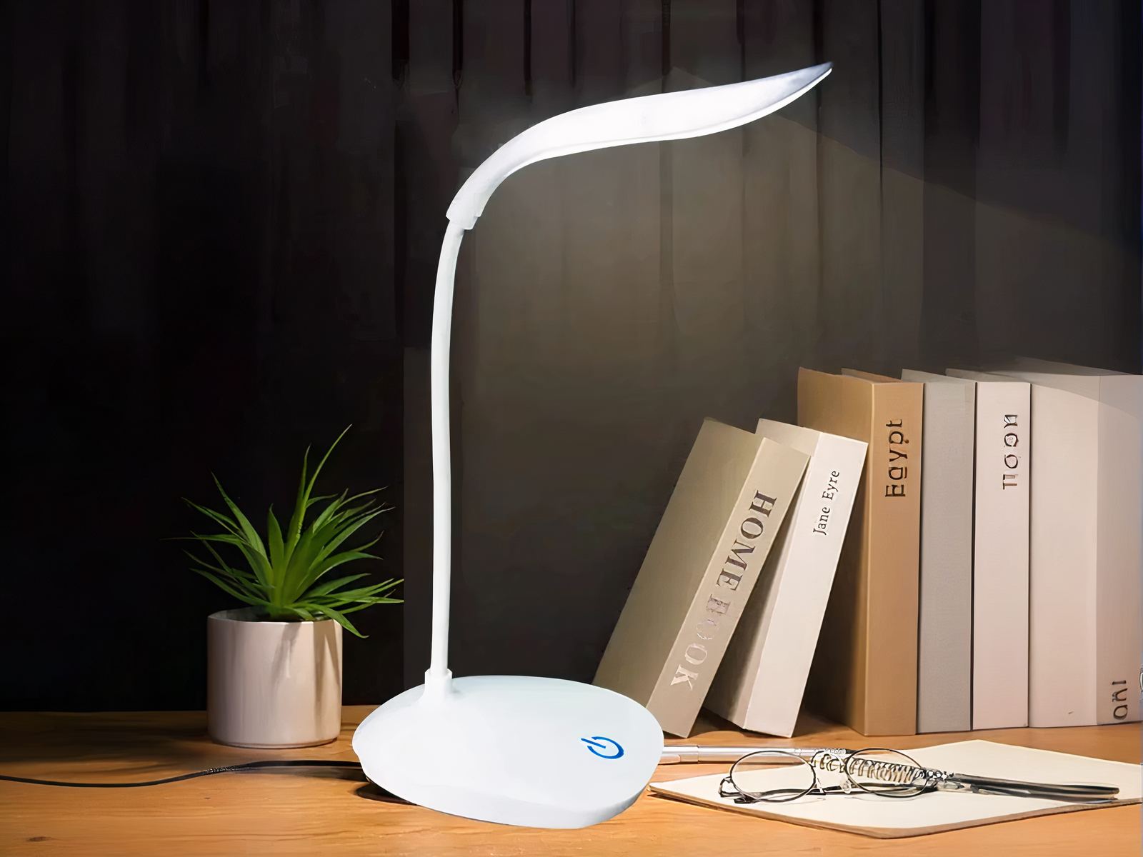 Lampe de bureau LED tactile et design Lampe de bureau LED tactile et design allumée sur un bureau dans le noir avec des livres posés à côté