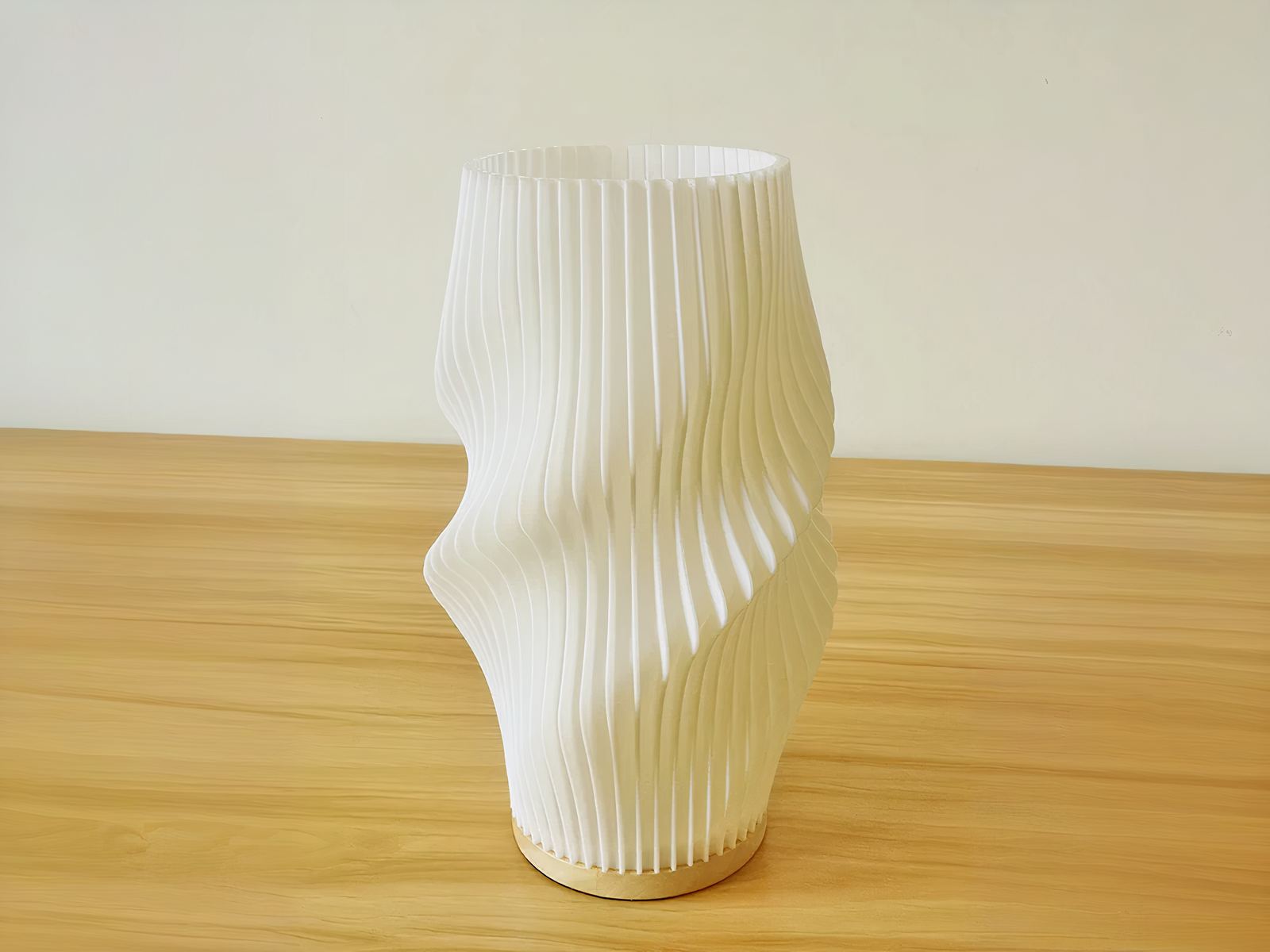 Lampe de chevet LED blanche élégante et design plissé, sur une table en bois.