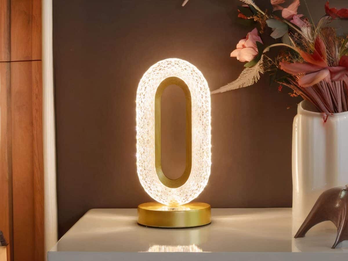 Lampe de chevet LED design en métal doré, sur une table.