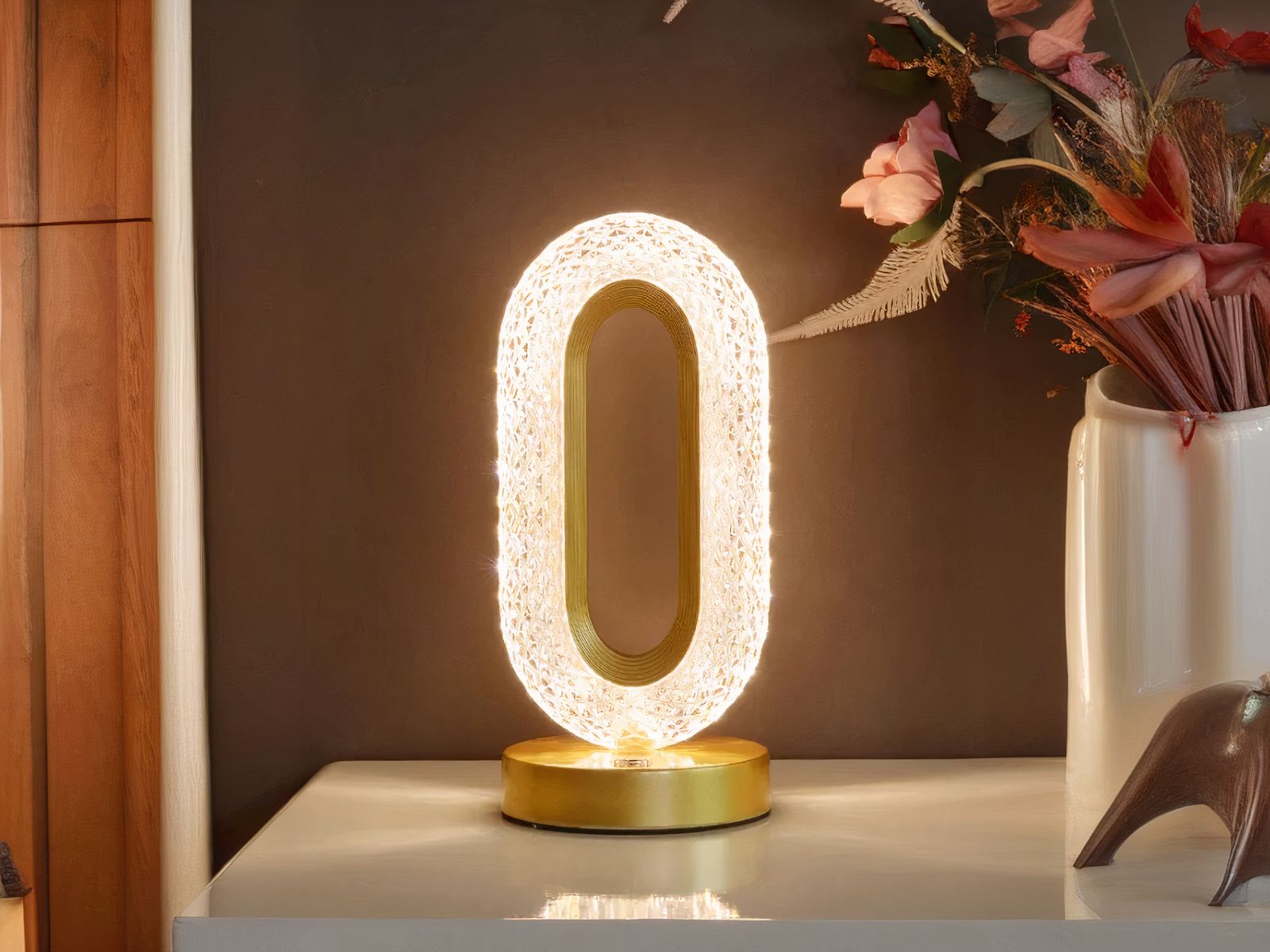 Lampe de chevet LED design en métal doré, sur une table.