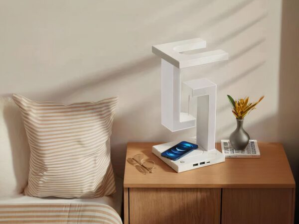 Lampe de chevet LED design et décorative blanche, sur une table de chevet à côté d'un lit.