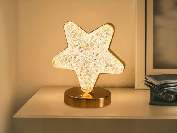 Lampe de chevet LED élégante en forme d'étoile dorée, sur une table.