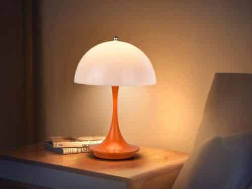 Lampe de chevet LED en forme de champignon orange, sur une table de chevet.