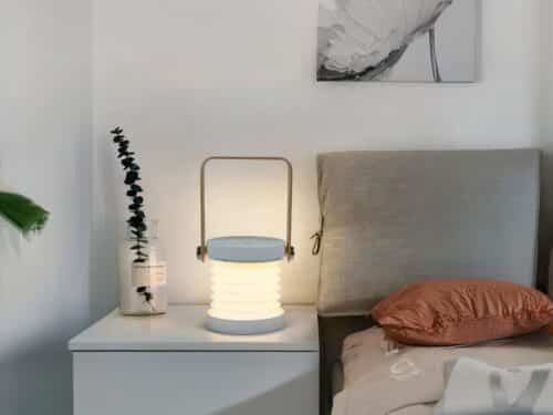Lampe de chevet LED pliante et design blanc, sur une table de chevet.