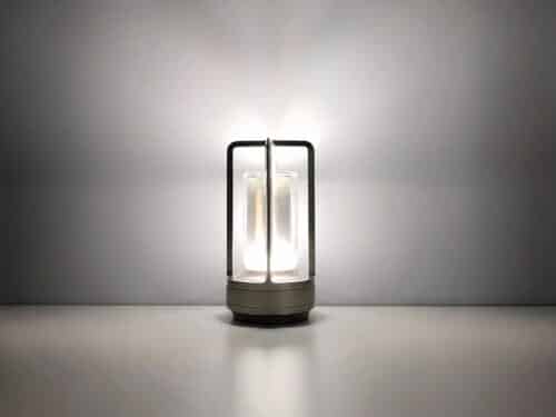 Lampe de chevet LED style lanterne en aluminium argenté, sur un fond gris.