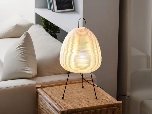 Lampe de chevet LED style lanterne japonaise blanche, sur une table en bois à côté d'un lit.