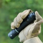 Lampe torche LED étanche et durable Lampe torche LED étanche et durable tenue dans une main avec gant sur fond vert