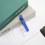 Lampe torche LED petit format avec clip intégré Lampe torche LED petit format avec clip intégré bleue sur une table contre des livres