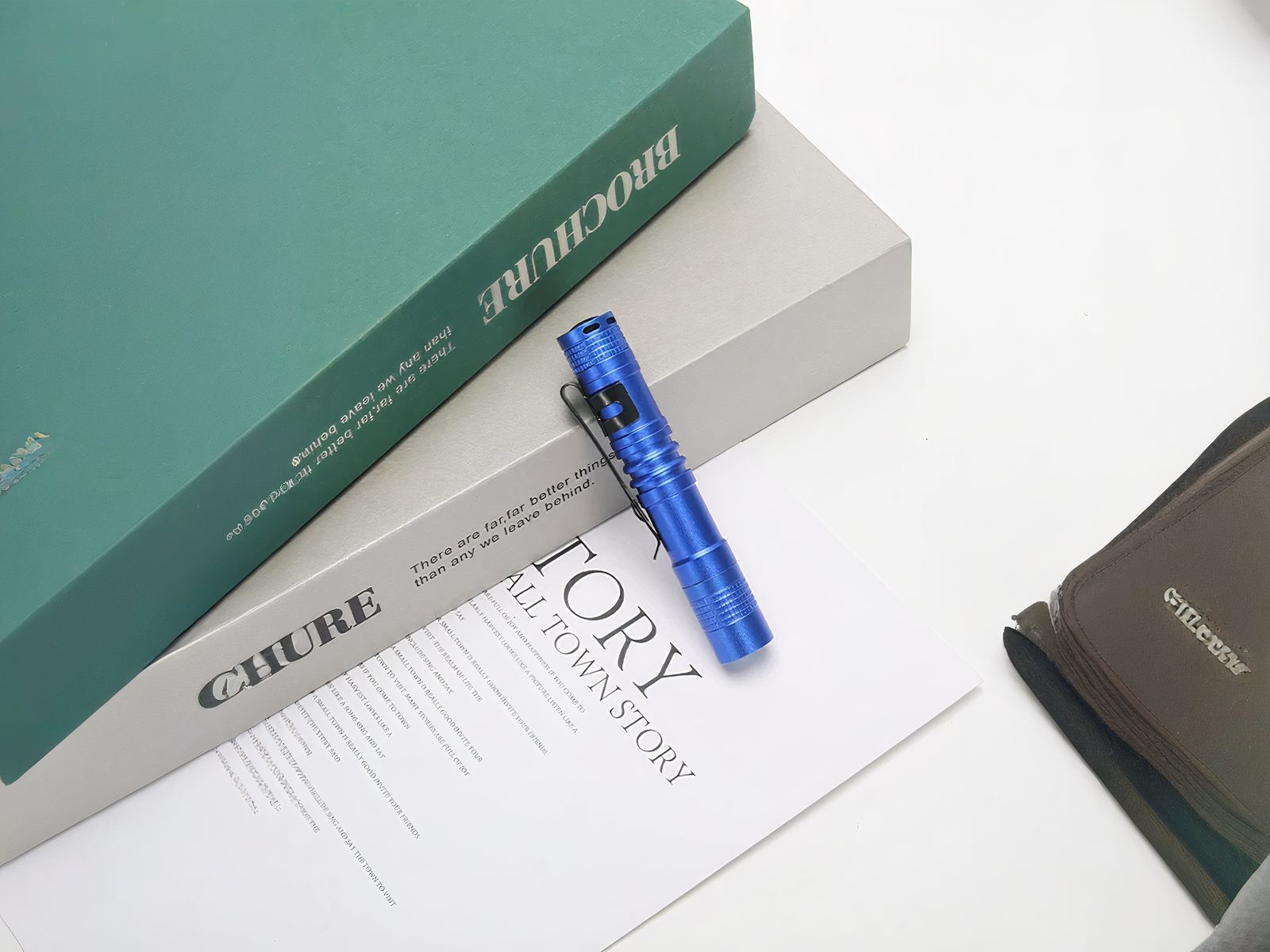 Lampe torche LED petit format avec clip intégré bleue sur une table contre des livres