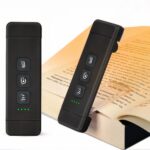 Liseuse LED multifonction avec minuterie Liseuse LED noire allumée et glissé dans le page d'un livre grâce à sa pince conçue pour.