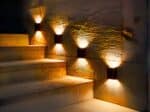 Lot de 4 appliques LED solaires noires design et étanches, le long d'un escalier.