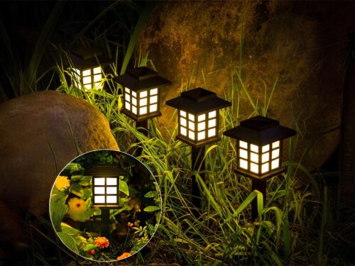Lot de 4 lampes LED solaires noires style lanternes design, dans un massif.