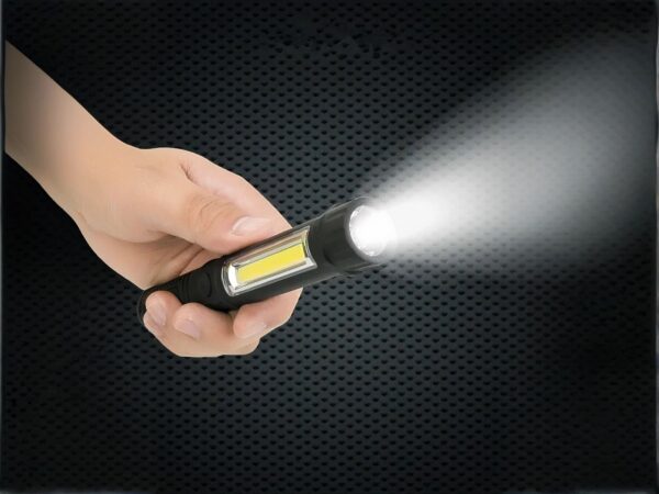 Mini lampe led multifonctionnelle étanche et noire, tenue dans une main, projetant une lumière blanche, sur un fond noir.