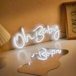 Néon LED blanche avec inscription Oh Baby Néon LED Blanche avec inscription Oh Baby, sur une table posé contre un mur.