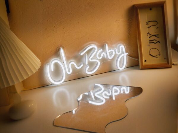 Néon LED Blanche avec inscription Oh Baby, sur une table posé contre un mur.